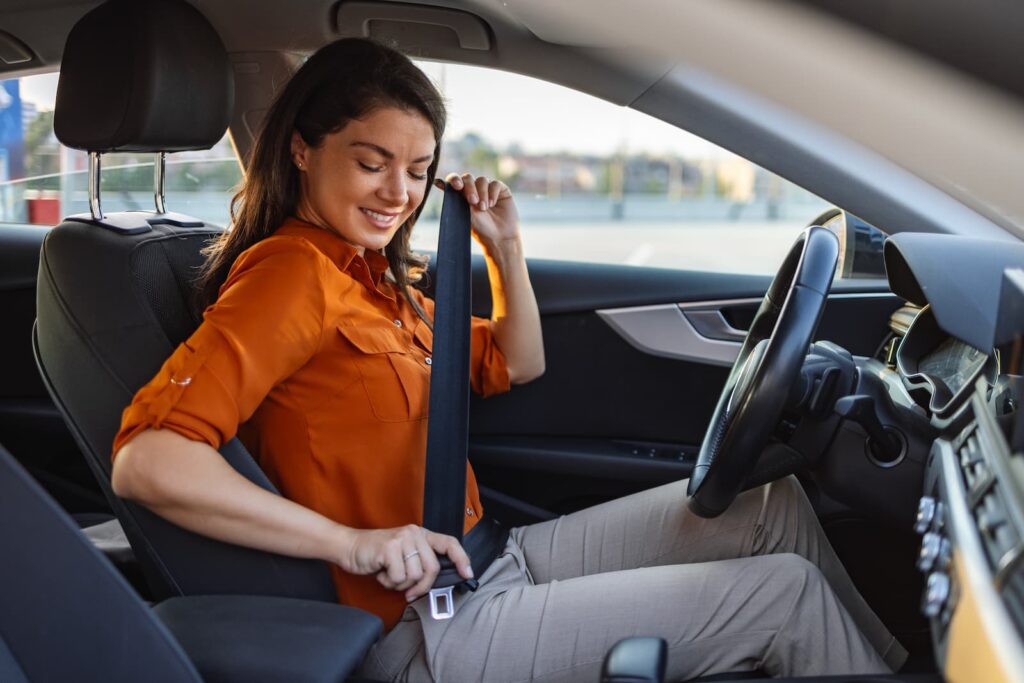 A women fastening her seatbelt in a parked car