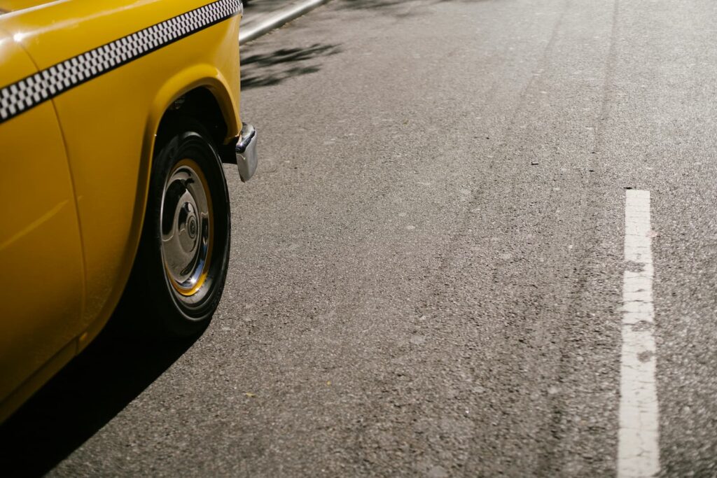 A yellow taxi driving on a concrete road