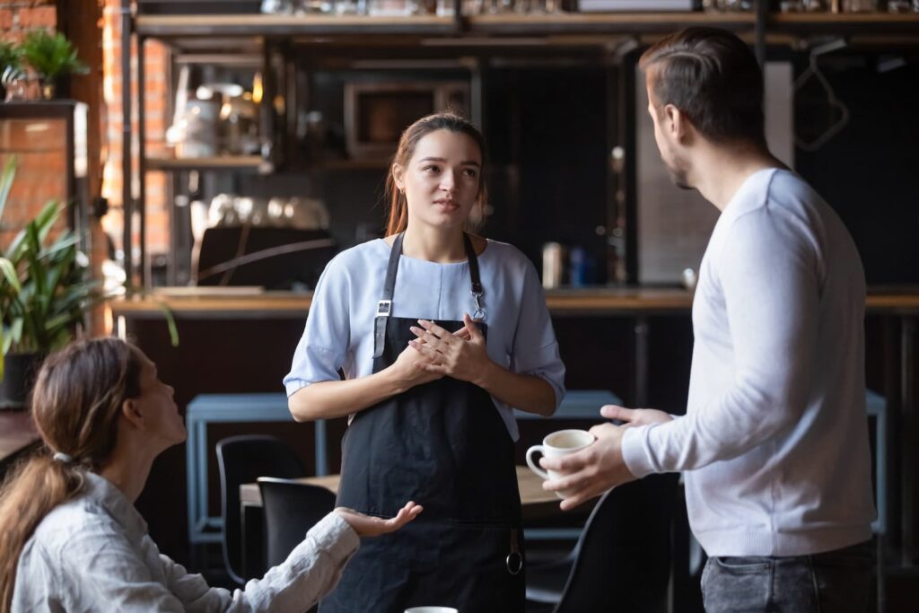 A waitress saying sorry to upset customers