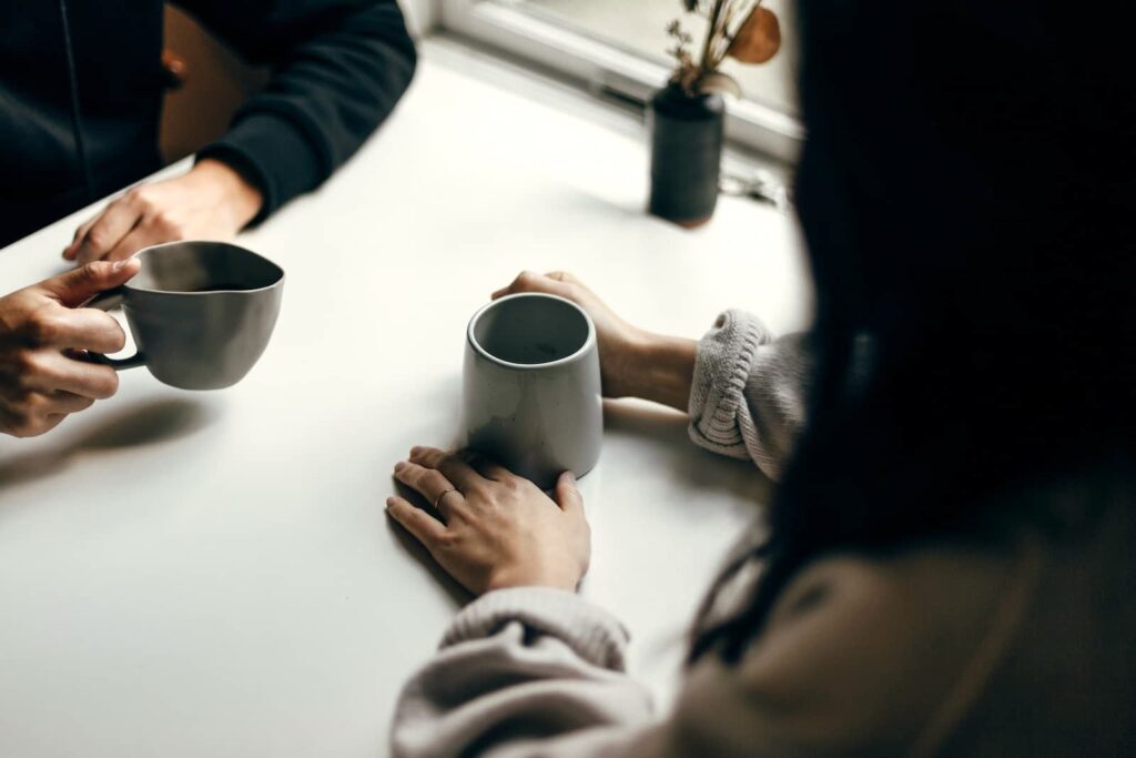 Two people keeping a conversation going while seated and drinking coffee