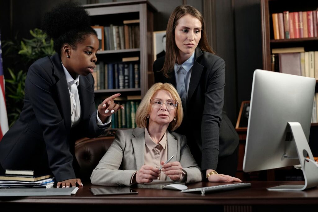 Three professionals looking at a computer screen in an office