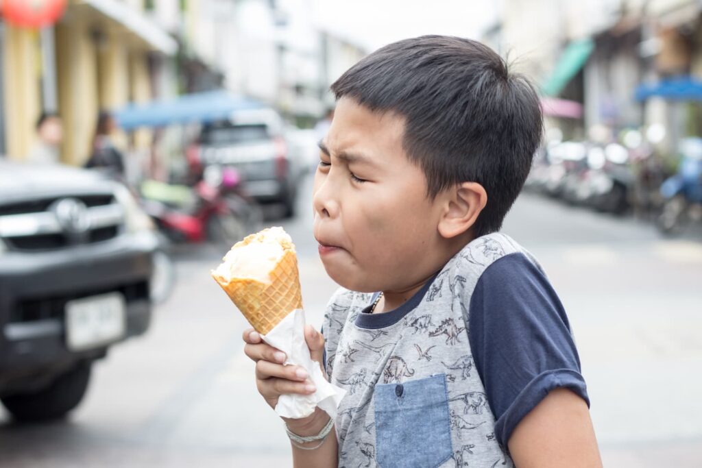 A young boy with a brain freeze from eating ice cream