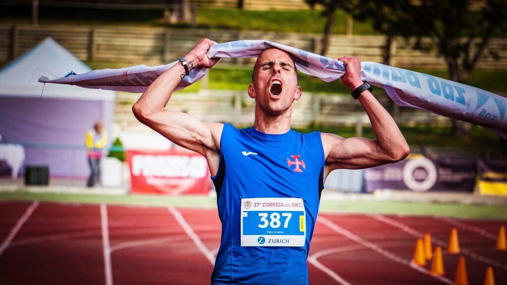 A man running on a track yells as he crosses the finish line