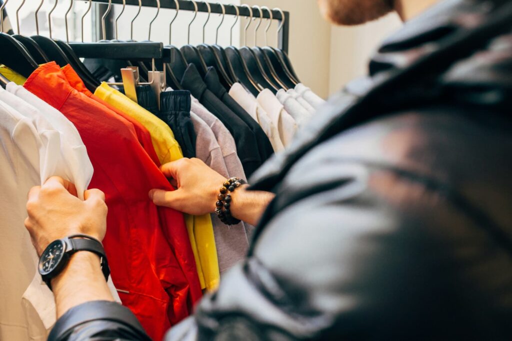 A man looking through clothes hanging on a rack